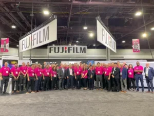 a group of people standing under fujifilm signs at the PRINTED United Expo