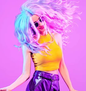 a woman with colorful hair and sunglasses is dancing in front of a purple background